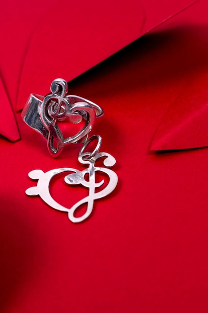 Valentine39s day background Vertical photo of love ring with pendant and red hearts on red love background