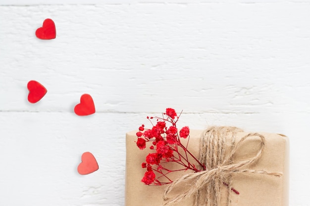 흰색 나무 배경에 하트와 붉은 꽃이 있는 공예 종이의 Valentine39s Day flatlay 선물 상자