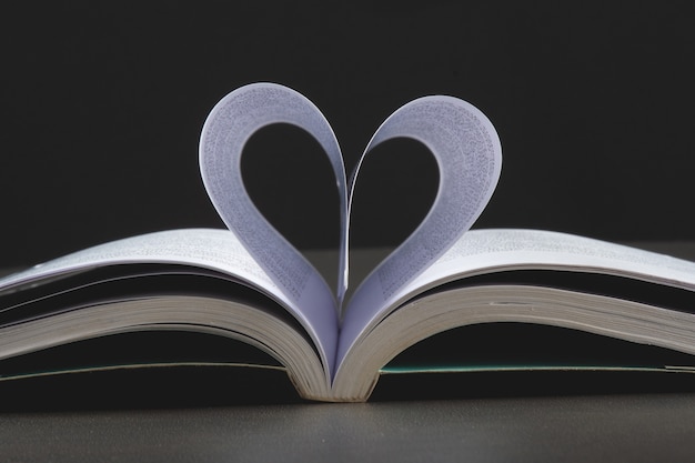 Sfondo di san valentino con libro aperto e pagine a forma di cuore.