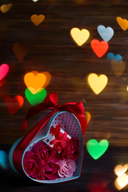 Valentines background with red hearts and rose in gift box on dark wooden background