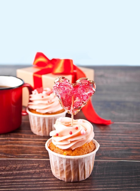 Valentines cupcakes cream cheese frosting decorated with heart candy lollipop on the wooden background