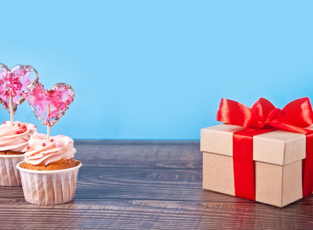 Valentines cupcakes roomkaas glazuur versierd met hart snoep lolly en geschenkdoos. kopieer ruimte.
