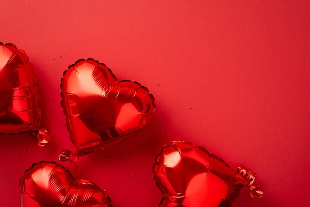 Концепция атмосферы Дня святого Валентина Сверху фото блестящих воздушных шаров в форме сердца и блестки на изолированном красном фоне с кописпасом