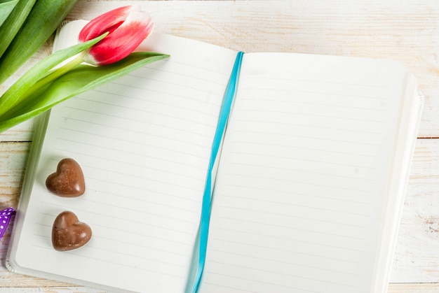 Valentines day background for congratulations, greeting cards. Fresh spring tulips flowers with chocolate hearts candy