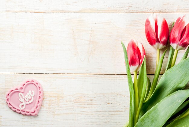 Valentines day background for congratulations, greeting cards. Fresh spring tulips flowers with pink chocolate candy