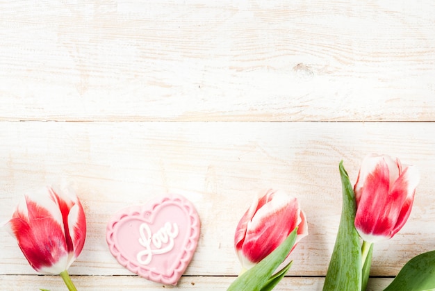 Valentines day background for congratulations, greeting cards. Fresh spring tulips flowers with pink chocolate candy