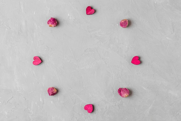 День Святого Валентина фон. Рама из сушеных цветов пиона и деревянных сердец на сером бетонном фоне. минимальная концепция. вид сверху с копией пространства