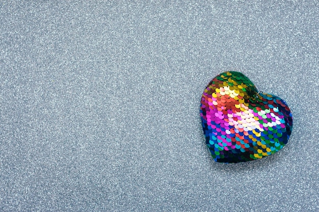 Valentines Day background, mockup with one Lgbt rainbow heart on silver shiny glitter background. Valentine Day, love, romance, dating concept, copy space