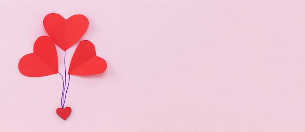 バレンタインデーの背景。パステルピンクの背景に赤いハート。バレンタインデーのコンセプト。フラットレイ、上面図、コピースペース。