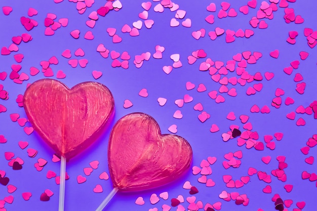 Valentines Day background. Two candy hearts with glitter on purple backdrop. Top view, copy space