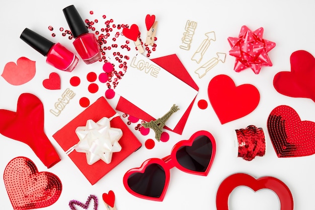 Valentines day background with card, hearts, confetti and party accessories in red colors.  Flat lay, top view