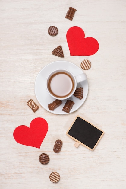 Valentines Day background with chocolate balls, coffee cup, red hearts and notebook