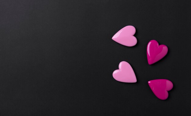 Valentines day background with pink hearts on black copy space background.