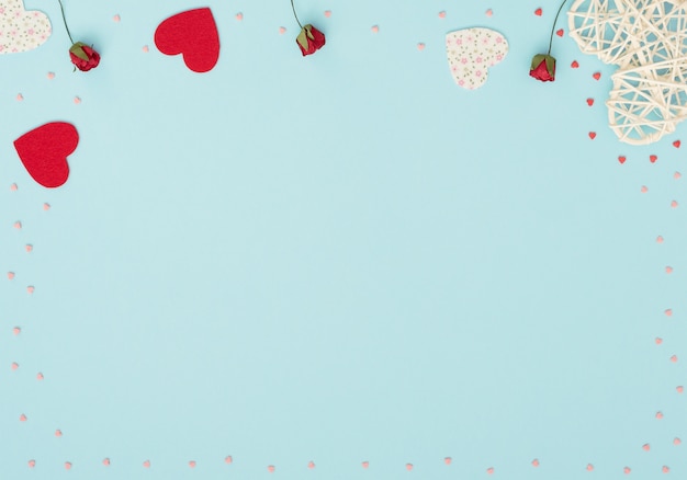 Valentines Day background with rattan and felt hearts, red roses and small red and pink hearts