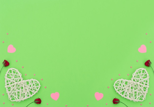 Valentines Day background with rattan and paper hearts, red roses and small pink hearts