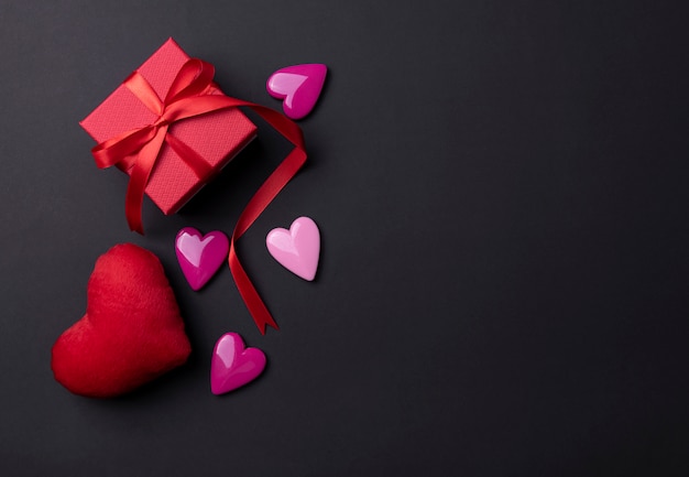 Valentines day background with red hearts and gift on black copy space background.