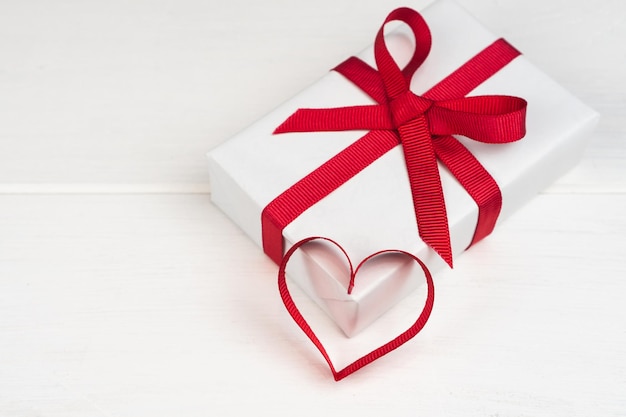 Valentines Day or birthday concept with copy space Red ribbon heart and gift box on white wood