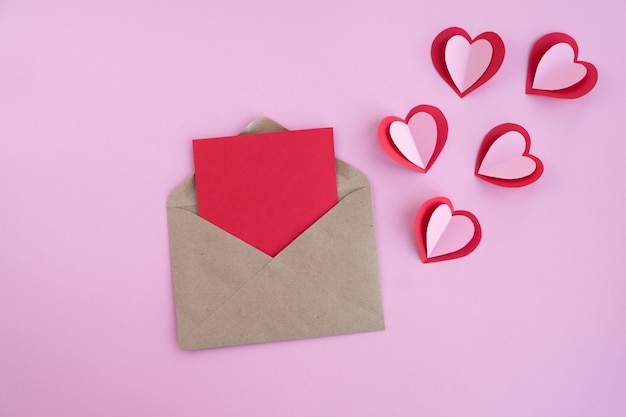 Valentines day. blank card with envelope and hearts on pink surface