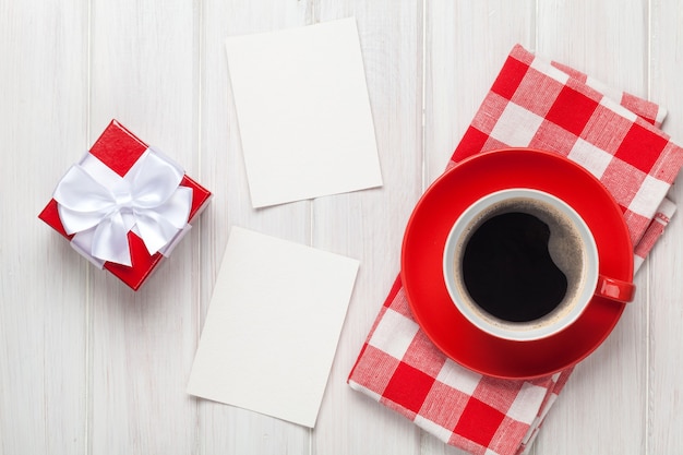 Valentines day blank photo frames, coffee cup and gift box over white wooden table