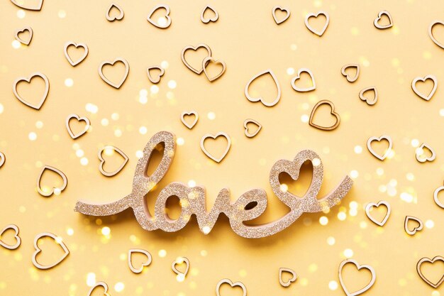 Valentines Day celebration concept. Wooden hearts and the word LOVE on a yellow background.