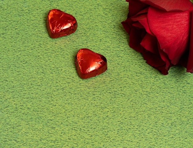 valentines day chocolates and rose on green background