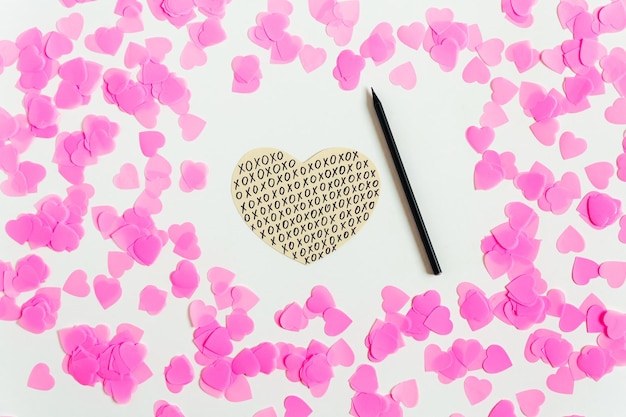 Valentines day composition White background with pink confetti hand drawn paper heart and pencil Top view