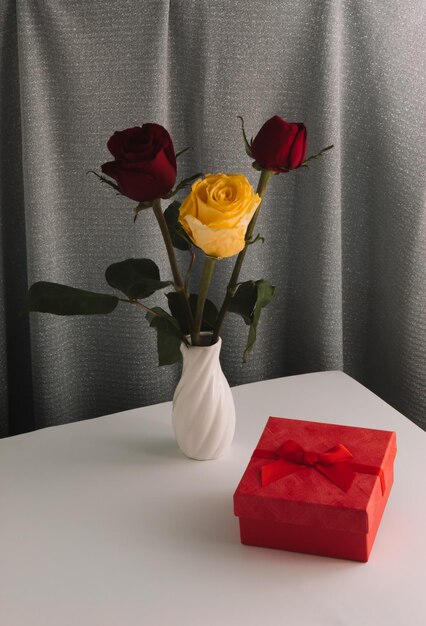 Valentines Day composition with red and yellow rose  in a vase on the table gift box  Womens Day