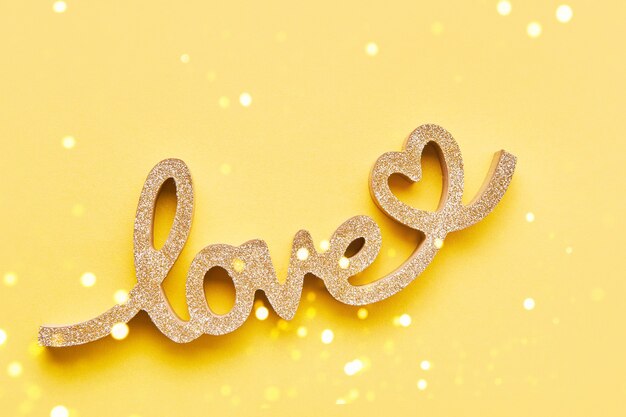 valentines day concept background. golden word love on yellow background. top view, copy space
