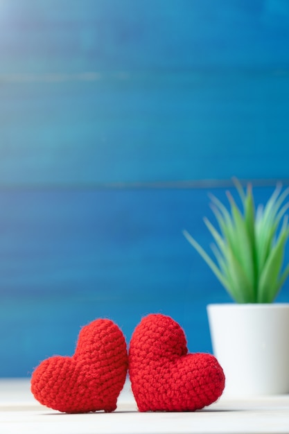 Valentines day concept. hand make two yarn red heart in front of white pot