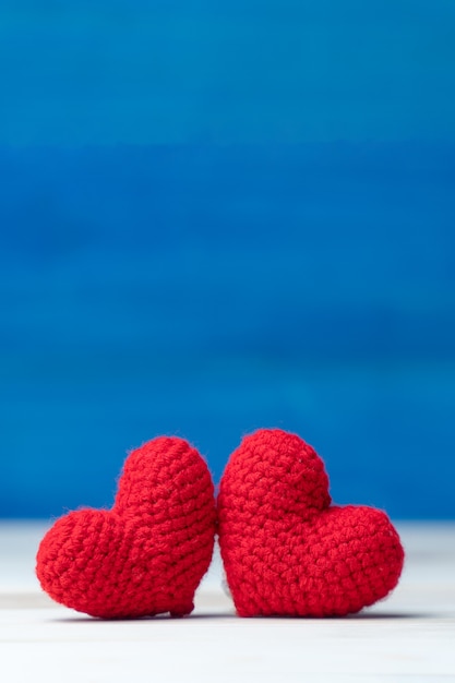 발렌타인 데이 컨셉입니다. 손 나무 테이블에 두 개의 원사 붉은 심장 만들기