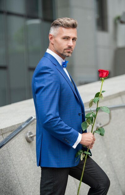 Valentines day concept mature tuxedo man with valentines rose flower gift for valentines day