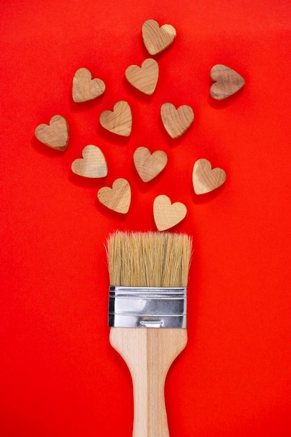 Valentines Day concept  Paint brush drawing with wooden hearts on a red background