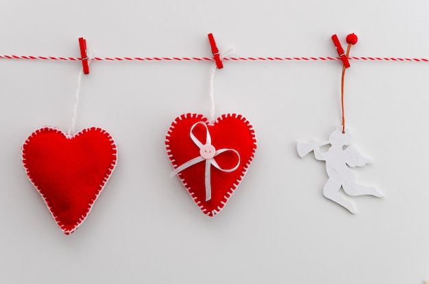 Valentines day concept. Red felt hearts and angel on rope with clothespin. 