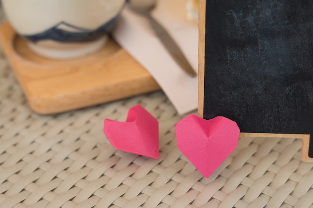 バレンタインデーのコンセプト、コーヒーショップの部屋のヴィンテージテーブルの背景に赤い紙の心