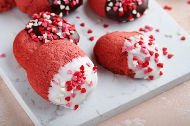 Foto biscotti di san valentino biscotti di pasta frolla con glassa di cioccolato bianco e fondente e spruzzi di cuore su piatto su sfondo rosa festa della mamma festa della donna dolci vacanze cottura vista dall'alto