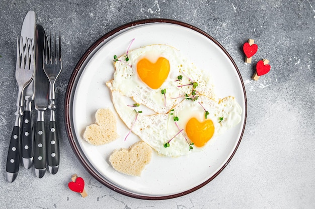 Valentines day egg breakfast on the table scrambled fried eggs heart shape love holiday decoration