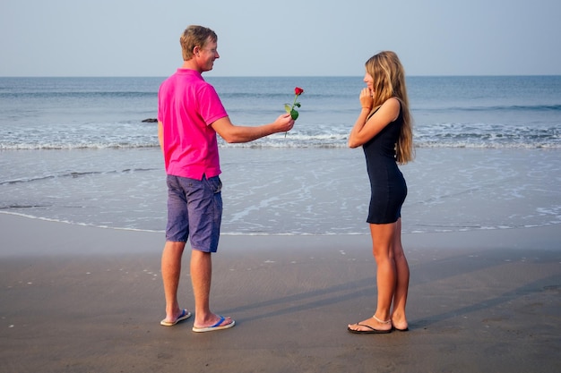 Valentines Day February 14th a man gives a woman a rose standing on a beach by the sea summer morning