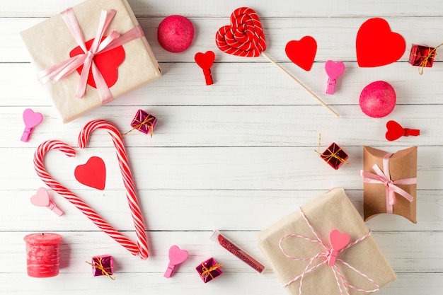 Valentines day. Frame of red hearts, gift box with ribbon and candy sweets on white