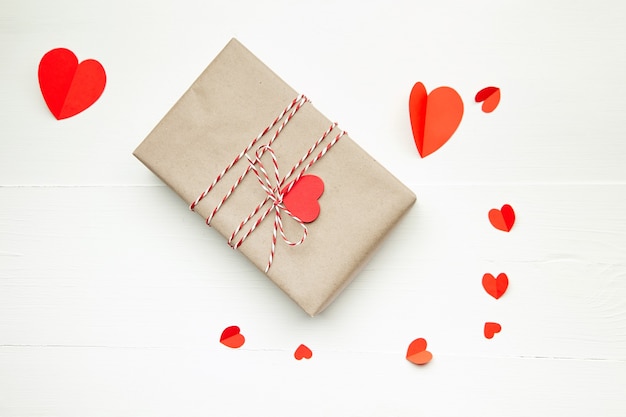 Valentines day gift box decorated with red hearts on white wooden table