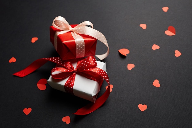 Valentines day gift boxes with red hearts on black paper background