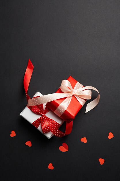 Valentines day gift boxes with red hearts on black paper background