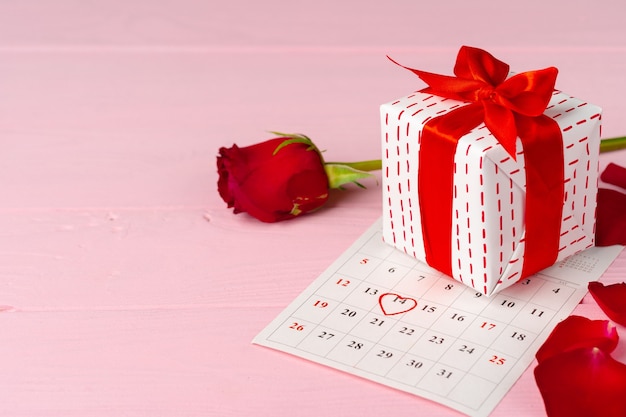 Valentines day gift and rose on wooden table close up