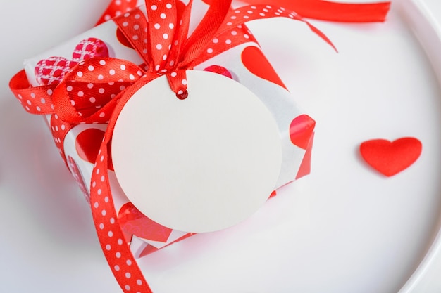 Regalo di san valentino con mockup di etichetta regalo bianca rotonda su piatto bianco con cuore rosso vendita black friday