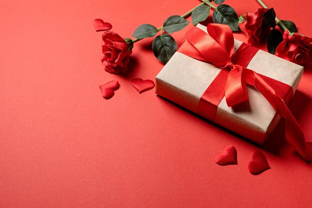 バレンタインデーの贈り物は赤い背景のコピースペースにバラとコンフェッティです