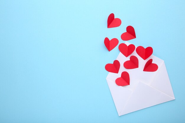 Valentines day greeting card. Handmaded red hearts in envelope on blue background.