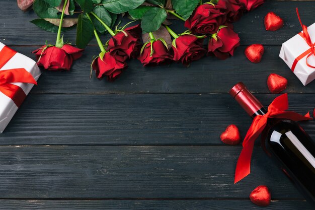 Valentines day greeting card, Red rose flowers, wine and gift box on wooden table.