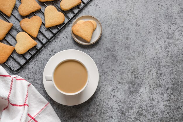 Valentines day greeting card with heart cookies and coffee cup on grey stone table.