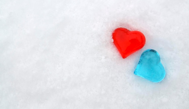 Foto biglietto di auguri per san valentino. decorazione di san valentino. due cuori di vetro decorativi sulla neve