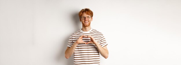 Valentines day happy boyfriend with red hair smiling and showing heart gesture i love you person