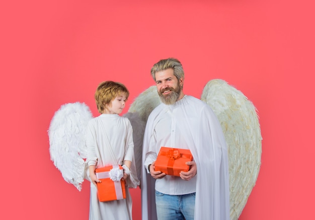 Фото День святого валентина маленький мальчик купидон дарит отцу подарок подарочную коробку на день отца счастливый отец в костюме ангела